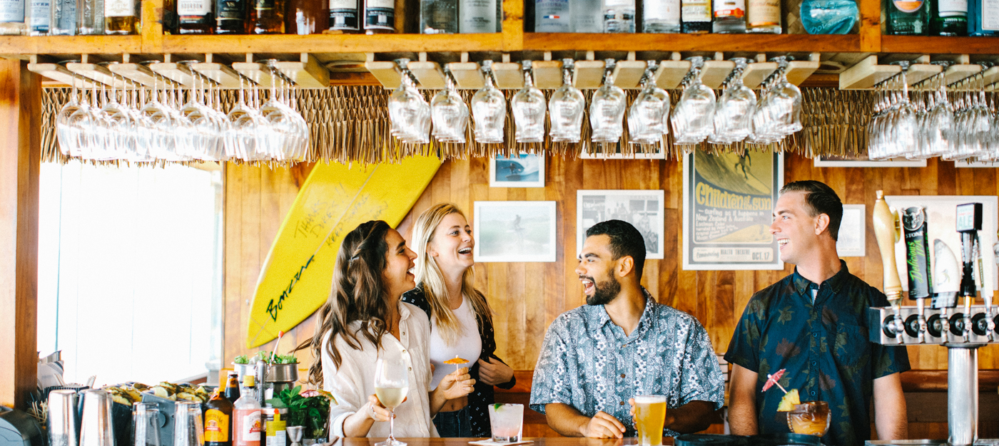 Four friends at the bar enjoying cocktails